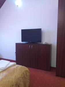 Habitación con cama y tocador con TV. en Motel din Darste, en Săcele