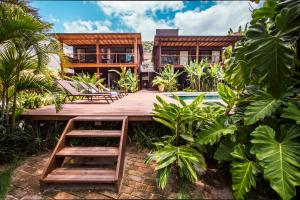 a home with a wooden deck and a house at Flat Pitanga in Camburi