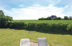 two white chairs sitting in the grass near a hedge at Holiday Home Vesterende V in Ballum