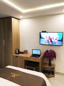 a bedroom with a bed and a desk with a laptop at Trang Ngan Hotel by THG in Danang