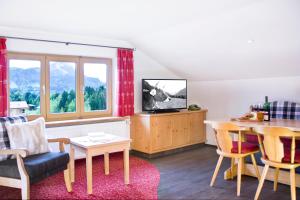a living room with a tv and a table at Ferienwohnungen Gästehaus Schraudolf in Oberstdorf