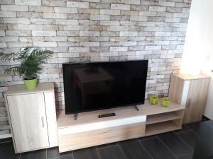 telewizor z płaskim ekranem siedzący na szczycie drewnianego centrum rozrywki w obiekcie Ferienwohnung Pusteblume w mieście Alpen