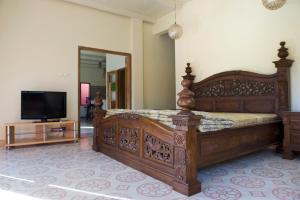 日惹的住宿－Villa Diamond，一间卧室配有一张大木床和电视。