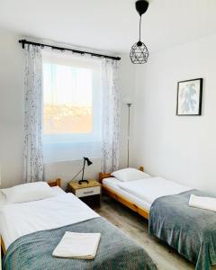 two beds in a room with a window at Gościniec i Restauracja Salton in Bochnia