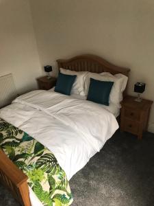 1 dormitorio con 1 cama con sábanas blancas y almohadas azules en Home on the Park en Mánchester
