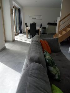 Kerautret Vian في Plougoulm: أريكة رمادية مع وسائد في غرفة المعيشة