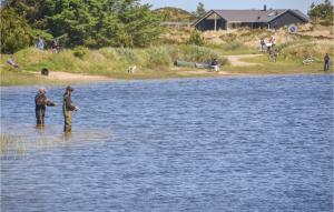 dos hombres están parados en el agua pescando en Lrkereden, en Hemmet