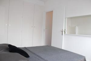 a bedroom with a bed with white cabinets and a mirror at Nice flat near Paris MCP in Joinville-le-Pont