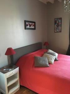 a bedroom with a red bed and a nightstand with two lamps at la p'tite maison in Feuguerolles-sur-Orne