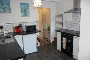 een keuken met zwarte aanrechtbladen en witte apparaten bij Candlelight in Minehead
