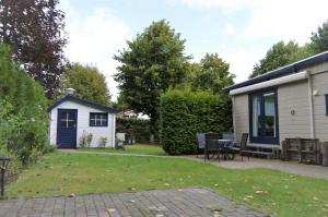 een achtertuin met een huis en een tafel en stoelen bij Chalet Bosrust in Wolfheze