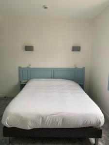 a bed with a blue headboard in a room at Hôtel La Sirène in Yport