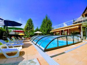 a swimming pool with chairs and umbrellas next to a building at Zöld sziget Apartmanház in Gyenesdiás