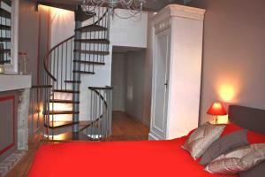 a bedroom with a red bed and a spiral staircase at la p'tite maison in Feuguerolles-sur-Orne