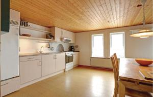 ÅkirkebyにあるStangegaardの白いキャビネットと木製の天井が備わるキッチン