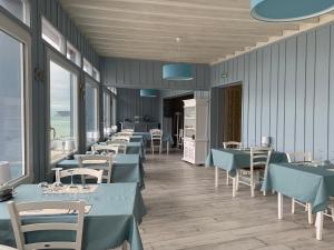 - une salle à manger avec des tables, des chaises et des fenêtres dans l'établissement Hôtel La Sirène, à Yport
