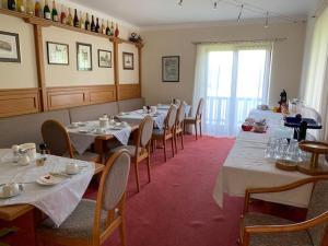 une salle à manger avec de longues tables et chaises ainsi qu'une fenêtre dans l'établissement Hotel Garni Haus am Wald, à Reifnitz