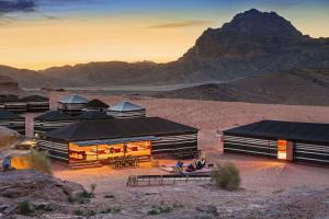 a group of buildings in the desert with a mountain in the background at Mohammed Mutlak Camp in Wadi Rum