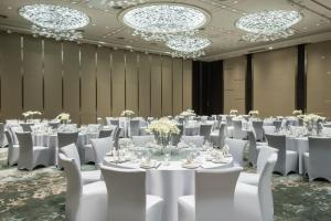 um salão de baile com mesas e cadeiras brancas e lustres em Crowne Plaza Chongqing New North Zone, an IHG Hotel em Chongqing