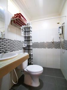 a white bathroom with a toilet and a sink at Casa Idaman Motel in Pantai Cenang