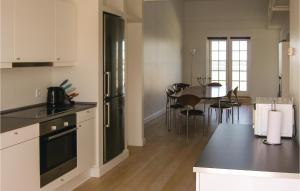 BagenkopにあるAmazing Apartment In Bagenkop With 3 Bedrooms And Saunaのキッチン(黒い冷蔵庫、テーブル、椅子付)