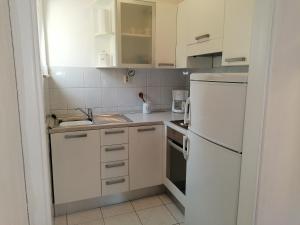 cocina pequeña con armarios blancos y nevera blanca en La Petite Maison, en Splitska 14 fotos más