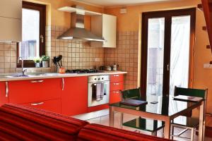 eine Küche mit roten Schränken und einem Tisch in der Küche in der Unterkunft Sotto al Portico - YourPlace Abruzzo in Rocca San Giovanni