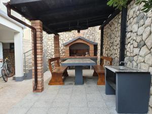 eine Terrasse mit einem Tisch und einem Steinofen in der Unterkunft Apartments Tramontana in Pag