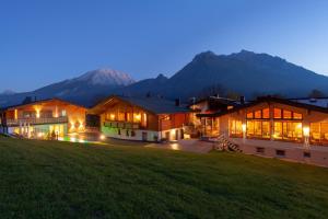 una casa con montañas en el fondo por la noche en Hotel Hindenburglinde, en Ramsau