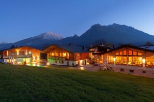 a house with mountains in the background at night at Hotel Hindenburglinde in Ramsau