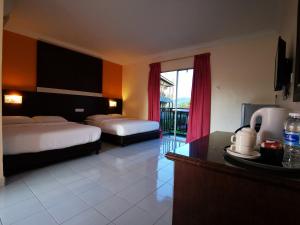 a hotel room with two beds and a kitchen with a table at Casa Idaman Motel in Pantai Cenang