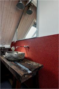 a bathroom with a stone sink on a red wall at Hofje Margo in Meliskerke