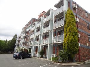 an apartment building with a car parked in a parking lot at Adina Place Motel Apartments in Launceston