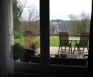 een raam met uitzicht op een patio met stoelen in de tuin bij Chambres La Belle Vue in Dinant