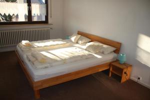 - un lit en bois avec des draps et des oreillers blancs dans l'établissement Ferienwohnung Friedrich, à Schonungen