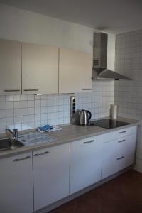 - une cuisine avec des placards blancs et un évier dans l'établissement Ferienwohnung Friedrich, à Schonungen
