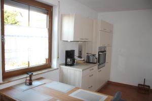 a kitchen with white cabinets and a table and a window at Ferienwohnung Friedrich in Schonungen +8 photos