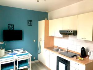 a kitchen with white cabinets and a blue wall at Le petit Bailleux in Braine