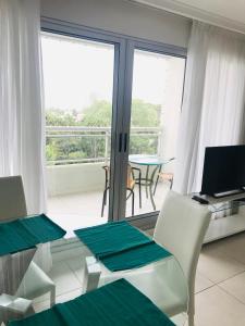 een woonkamer met een tafel en stoelen en een raam bij Cómodo apartamento en Torre Ocean Drive con todos los servicios in Punta del Este