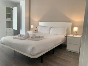 a bedroom with a large white bed with two lamps at Zerka Sendra in Valencia