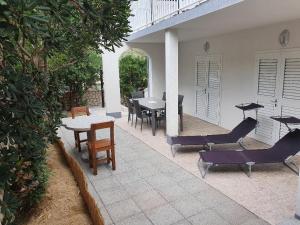 a patio with chairs and tables and a table and chairs at Apartments Tramontana in Pag