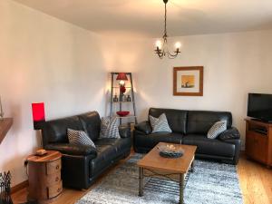 a living room with black leather couches and a table at Kesh Lakeside Cottage in Kesh