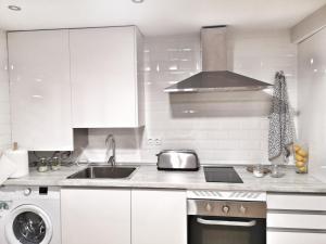 eine weiße Küche mit einer Spüle und einem Herd in der Unterkunft Apartamento Ilarcuris con patio privado in Toledo