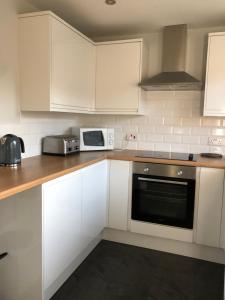 a kitchen with white cabinets and a stove and microwave at spacious 2 bedroom house in Shotton