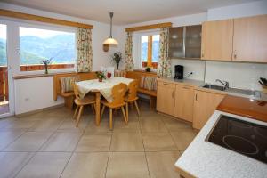 a kitchen with a table and chairs and a kitchen with mountains at Bio Kräuterhof Oberpalwitter in Barbiano