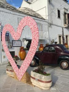 un signe en forme de cœur devant une voiture dans l'établissement Tipico Resort, à Alberobello