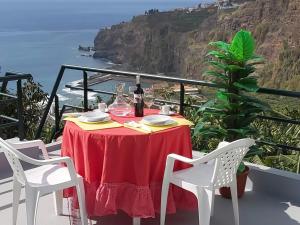 una mesa con mantel rojo y una botella de vino en Tabua Village Adventure Room #6 with Ocean View, en Ribeira Brava 9 fotos más
