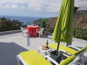 un patio con una mesa y una sombrilla verde en Tabua Village Adventure Room #6 with Ocean View, en Ribeira Brava