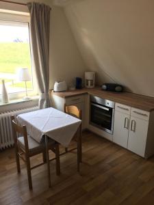 une cuisine avec une table et une cuisinière ainsi qu'une fenêtre dans l'établissement Kiekkast 3, à Norddeich