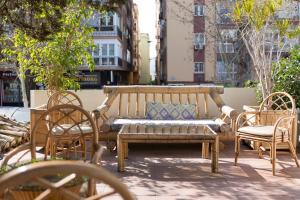 un banco de madera y sillas en un patio en Gala Placida 1923 en Granada